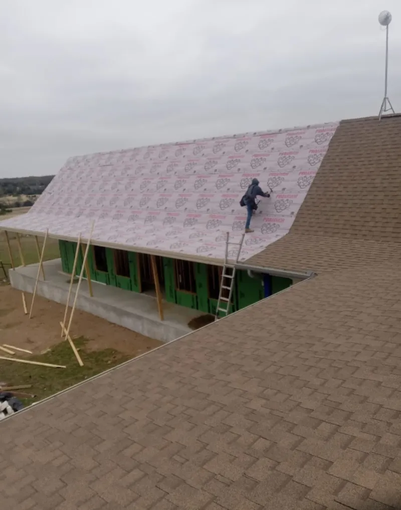 Worker preparing underlayment for a metal roof installation in Horsham